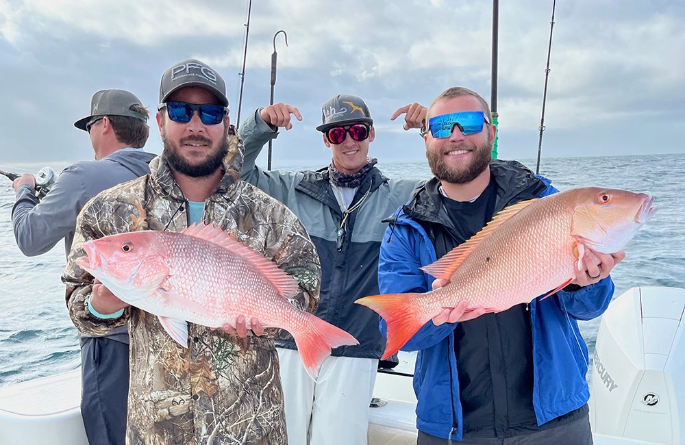 image of a fishing charter guests holding a red snappers that was caught while on a fishing charter with Changes 'N latitude