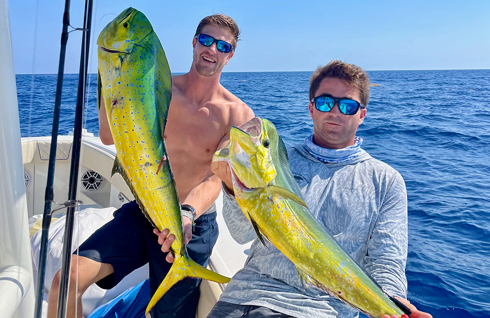 guests holding a mahi-mahi that was caught while on a fishing charter with Changes 'N latitude