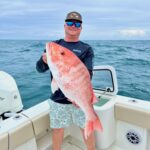 image of a fishing charter guest holding a red snapper that was caught while on a fishing charter with Changes 'N latitude