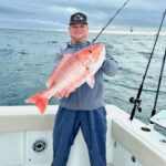 image of a fishing charter guest holding a red snapper that was caught while on a fishing charter with Changes 'N latitude
