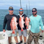 guests holding red snappers that were caught while on a fishing charter with Changes 'N latitude