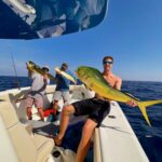 guests holding a mahi-mahi that was caught while on a fishing charter with Changes 'N latitude
