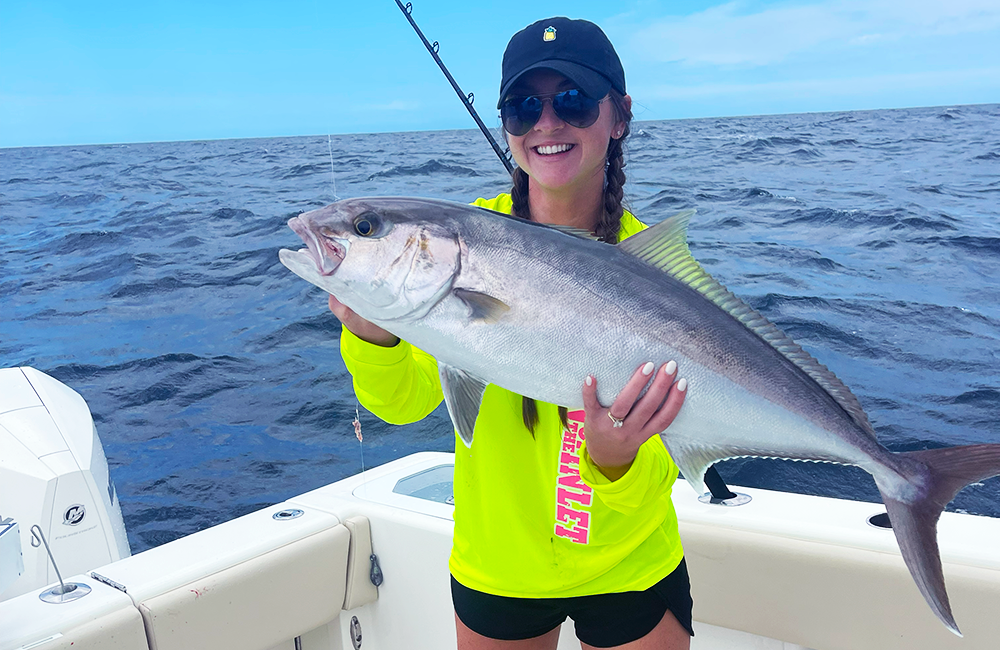 image of a fishing charter guest holding an amberjack that was caught while on a fishing charter with Changes 'N latitude